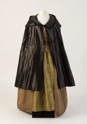 Black silk satin cape, worn with olive green silk quilted petticoat, 1760s